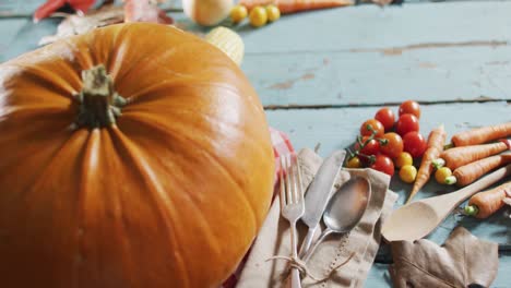 Close-up-view-of-pumpkin,-multiple-food-ingredients-and-cutlery-on-wooden-surface