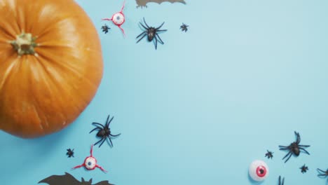 Close-up-view-of-pumpkin-and-halloween-toys-against-blue-background