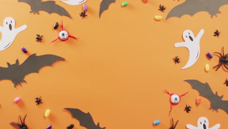 Nahaufnahme-Mehrerer-Halloween-Süßigkeiten-Und-Spielzeuge-Vor-Orangefarbenem-Hintergrund