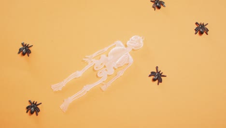 Multiple-skeleton-and-spider-toys-with-copy-space-against-orange-background