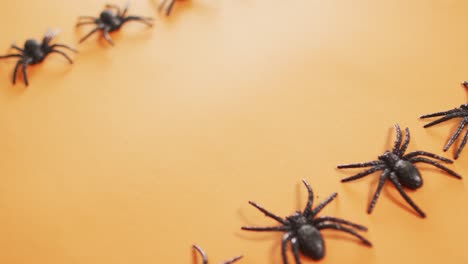 Close-up-of-multiple-spider-toys-with-copy-space-against-orange-background
