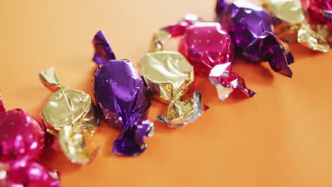 Close-up-of-multiple-halloween-candies-with-copy-space-against-orange-background