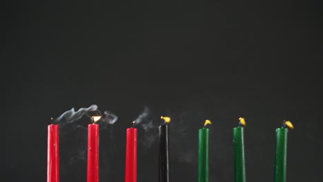 Composition-of-halloween-green,-black-and-red-lit-candles-being-blown-off-against-black-background