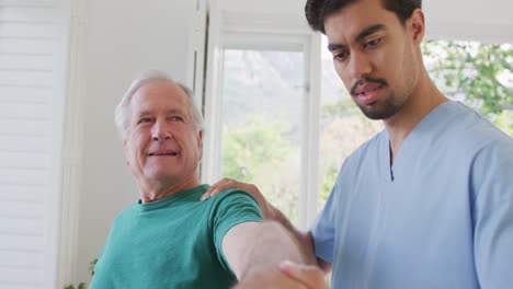 Männlicher-Physiotherapeut-Dreht-Die-Hand-Eines-Pensionierten-älteren-Mannes-Im-Uhrzeigersinn-Im-Altersheim