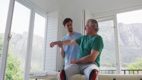 Slow-motion-shot-of-male-physiotherapist-helping-senior-patient-exercising-at-retirement-home
