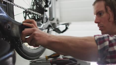 Fokussierter-Kaukasischer-Mann,-Der-Fahrrad-Mit-Werkzeugen-In-Der-Garage-Repariert