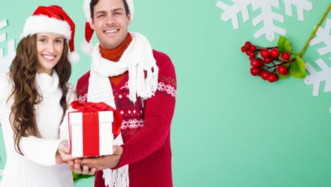 Composition-of-caucasian-couple-in-santa-hats-holding-christmas-present-on-green-background