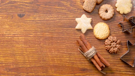 Composition-of-christmas-decorations-with-cinnamon,-cookies-and-pine-cones-on-wooden-background