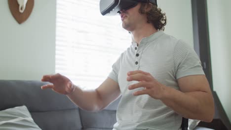 Happy-caucasian-disabled-man-in-wheelchair-wearing-vr-headset-in-living-room