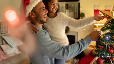 Animation-of-african-american-father-and-daughter-decorating-christmas-tree