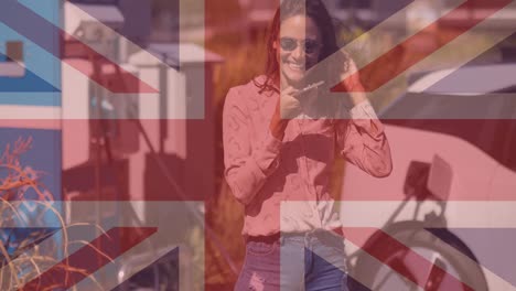 Bandera-De-Gran-Bretaña-Sobre-Una-Mujer-Usando-Un-Teléfono-Inteligente-Y-Cargando-Un-Auto-Eléctrico