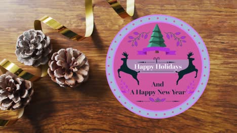 Animation-of-happy-holidays-christmas-text-on-round-tag-over-decorations-on-wooden-background