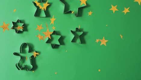 Animation-Von-Weihnachtssternen,-Die-über-Keksformen-Auf-Grünem-Hintergrund-Fallen