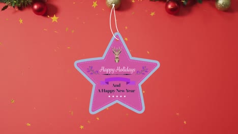 Animation-of-happy-holidays-christmas-text-on-star-tag-over-decorations-on-red-background
