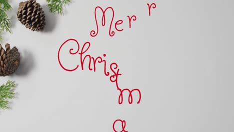 Animation-Des-Textes-„Frohe-Weihnachten“-über-Tannenzapfen-Auf-Weißem-Hintergrund