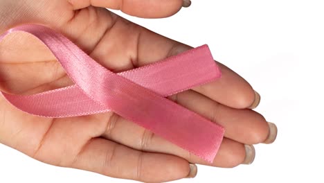 Animation-of-breast-cancer-awareness-text-on-pink-ribbon,-over-hand-of-woman-holding-pink-ribbon