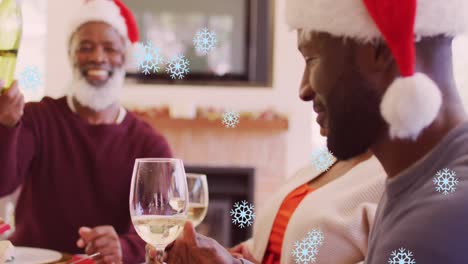 Animation-of-snow-falling-over-happy-african-american-family-wearing-santa-hats-and-having-dinner