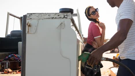 Diverse-man-and-woman-using-fuel-pump-filling-up-truck-at-petrol-station