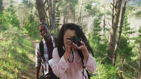 Smiling-diverse-couple-taking-photo-and-hiking-in-countryside