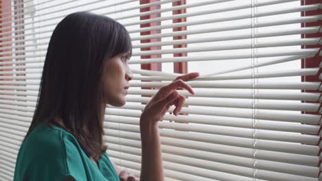 Biracial-female-patient-looking-through-window-alone-at-modern-dental-clinic
