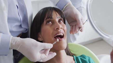 Male-dentist-examining-teeth-of-female-patient-at-modern-dental-clinic