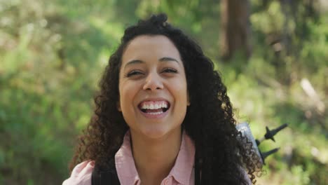 Portrait-of-smiling-biracial-woman-in-forest-during-hiking-in-countryside