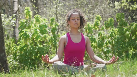 Biracial-woman-wearing-sportswear-and-meditating-in-forest