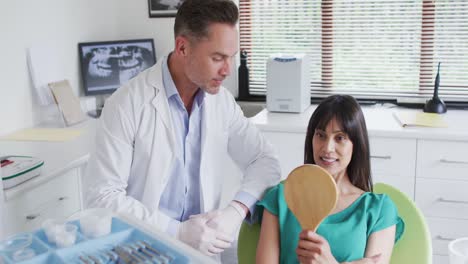 Smiling-caucasian-male-dentist-talking-with-female-patient-at-modern-dental-clinic