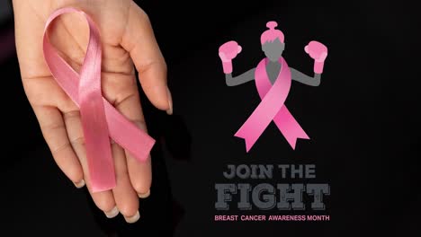 Animation-of-breast-cancer-awareness-text-over-hand-holding-pink-breast-cancer-ribbon