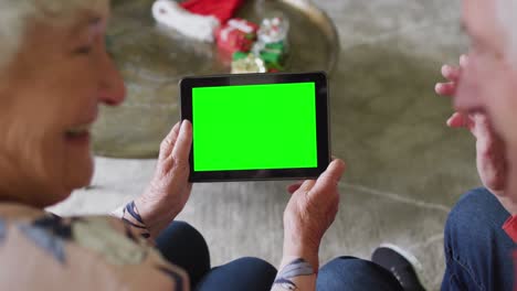 Smiling-senior-caucasian-couple-in-santa-hats-tablet-christmas-video-call,-with-green-screen