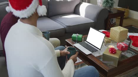 Happy-biracial-father-and-adult-son-making-laptop-christmas-video-call,-with-copy-space-on-screen
