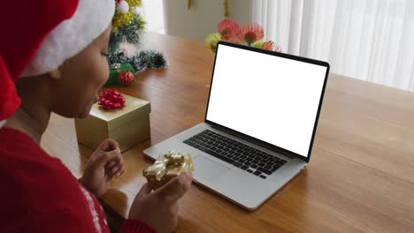 African-american-woman-in-santa-hat-making-laptop-christmas-video-call,-with-copy-space-on-screen