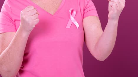 Video-of-midsection-of-caucasian-woman-with-raised-fists-wearing-pink-cancer-awareness-ribbon