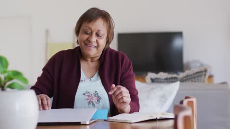 Glückliche-Afroamerikanische-ältere-Frau-Am-Esstisch,-Schließt-Laptop-Und-Lächelt