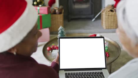 Smiling-diverse-senior-female-friends-making-laptop-christmas-video-call,-with-copy-space-on-screen