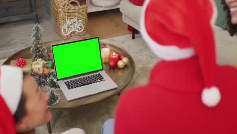 Lächelnde,-Verschiedene-Freunde-In-Weihnachtsmützen,-Die-Einen-Laptop-Weihnachtsvideoanruf-Tätigen,-Mit-Grünem-Bildschirm