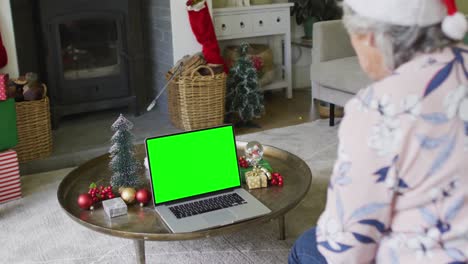 Ältere-Kaukasische-Frau-Mit-Weihnachtsmütze-Macht-Laptop-Weihnachtsvideoanruf,-Mit-Grünem-Bildschirm