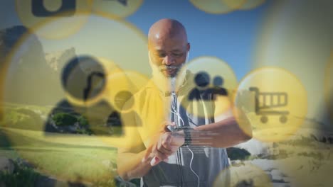 Animation-Von-Mediensymbolen-über-Einem-älteren-Afroamerikanischen-Mann-Mit-Kopfhörern-Am-Strand