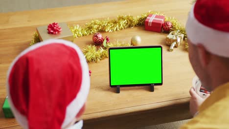 Kaukasischer-Vater-Und-Sohn-In-Weihnachtsmützen-Machen-Tablet-Weihnachtsvideoanruf,-Mit-Grünem-Bildschirm