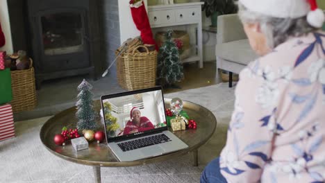 Senior-caucasian-woman-waving-and-using-laptop-for-christmas-video-call-with-woman-on-screen