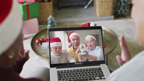 Diverse-senior-female-friends-waving-and-using-laptop-for-christmas-video-call-with-family-on-screen