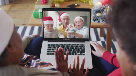 African-american-mother-and-daughter-using-laptop-for-christmas-video-call-with-family-on-screen