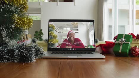 Mujer-Afroamericana-Sonriente-Con-Sombrero-De-Papá-Noel-En-Videollamada-Navideña-En-Una-Computadora-Portátil