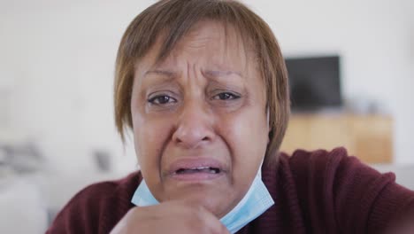 Verzweifelte,-Kranke-Afroamerikanische-Seniorin-Mit-Gesichtsmaske,-Die-Zu-Hause-Einen-Videoanruf-Tätigt