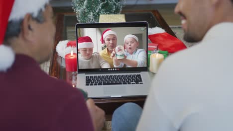 Biracial-Vater-Und-Sohn-Mit-Weihnachtsmützen-Nutzen-Laptop-Für-Weihnachtsvideoanruf-Mit-Der-Familie-Auf-Dem-Bildschirm