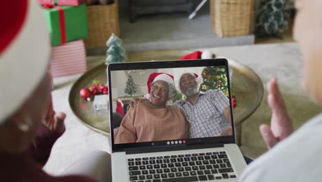 Verschiedene-ältere-Freundinnen-Winken-Und-Benutzen-Laptop-Für-Einen-Weihnachtsvideoanruf-Mit-Der-Familie-Auf-Dem-Bildschirm