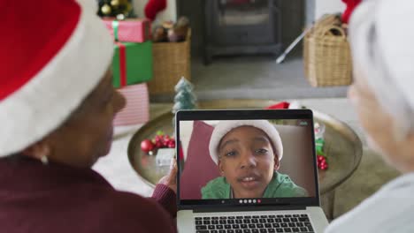 Smiling-diverse-senior-female-friends-using-laptop-for-christmas-video-call-with-boy-on-screen