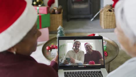 Smiling-diverse-senior-female-friends-using-laptop-for-christmas-video-call-with-family-on-screen