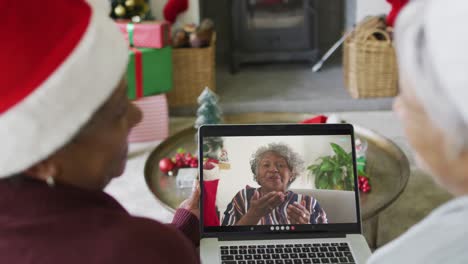 Lächelnde,-Verschiedene-ältere-Freundinnen,-Die-Einen-Laptop-Für-Einen-Weihnachtsvideoanruf-Mit-Einer-Frau-Auf-Dem-Bildschirm-Nutzen