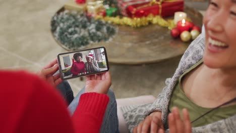 Smiling-asian-couple-using-smartphone-for-christmas-video-call-with-happy-family-on-screen
